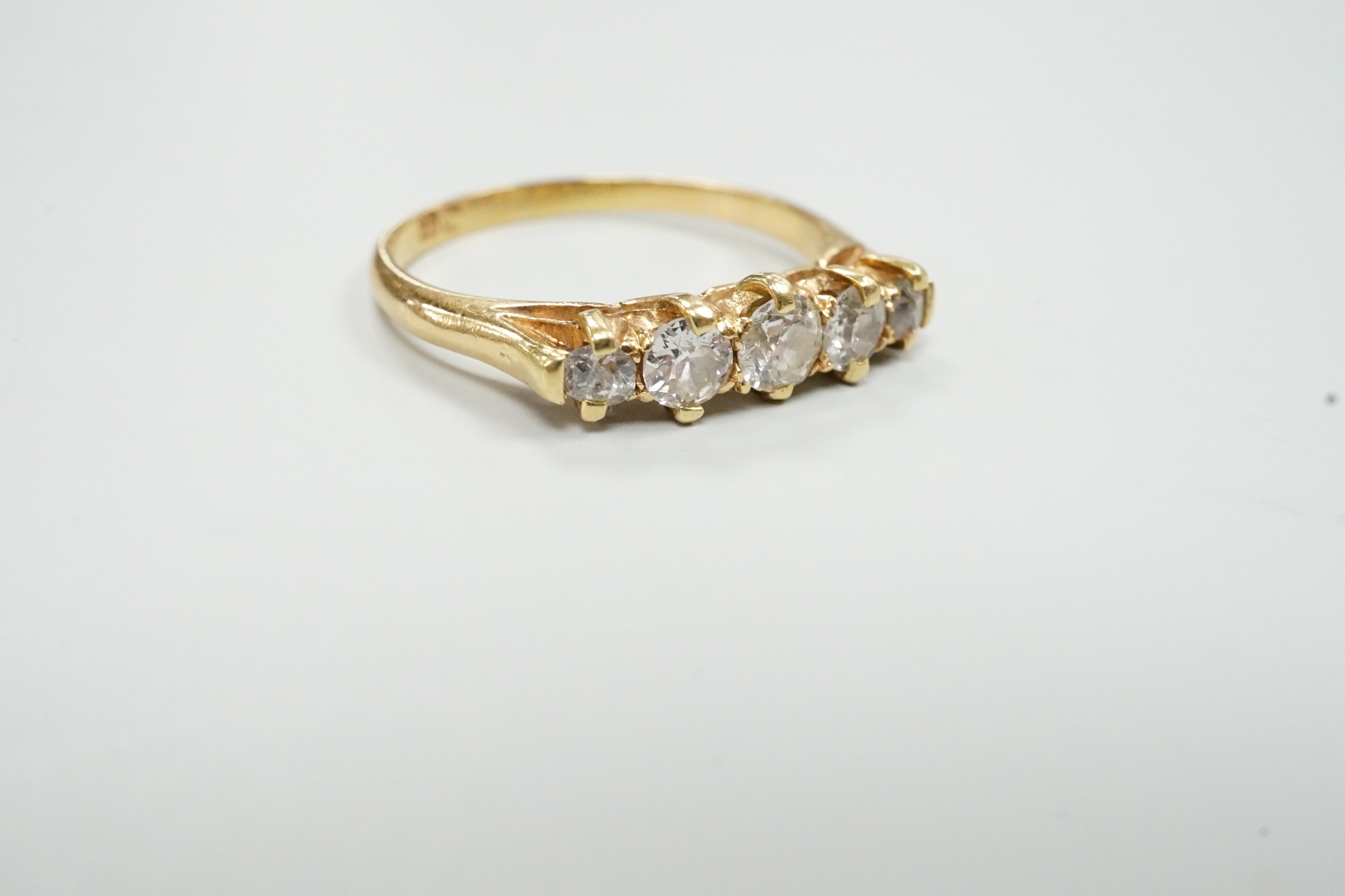 A gold and graduated five stone diamond set half hoop ring, size O/P, gross weight 2.8 grams.